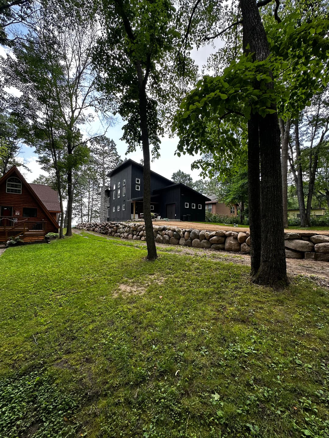 Modern black house surrounded by trees and a stone path in a scenic landscape.