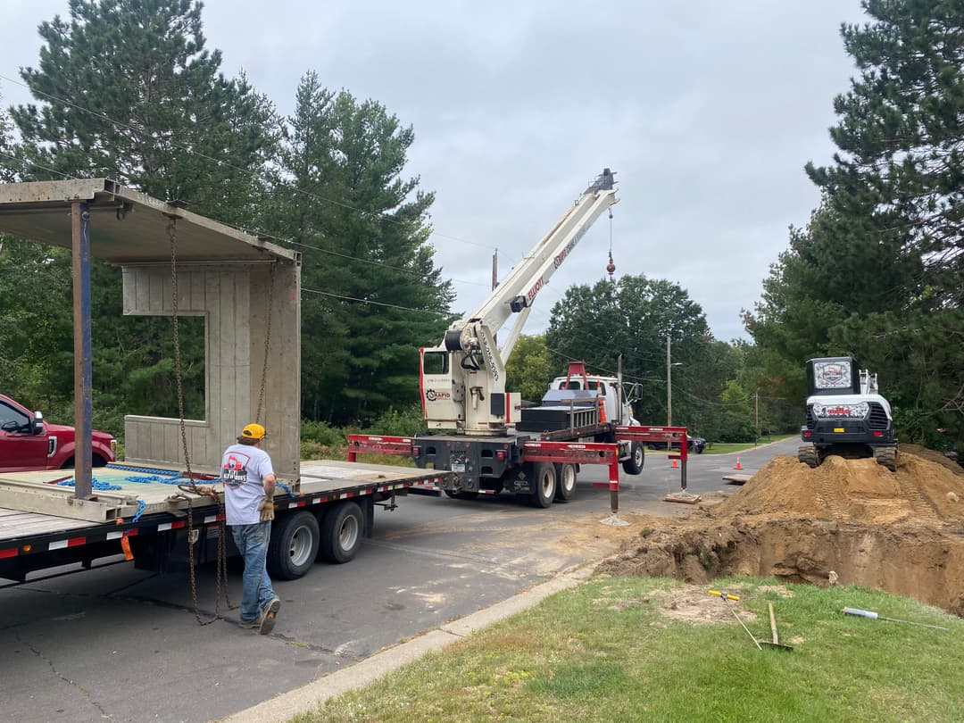Construction site with crane lifting modular building section onto a trailer.