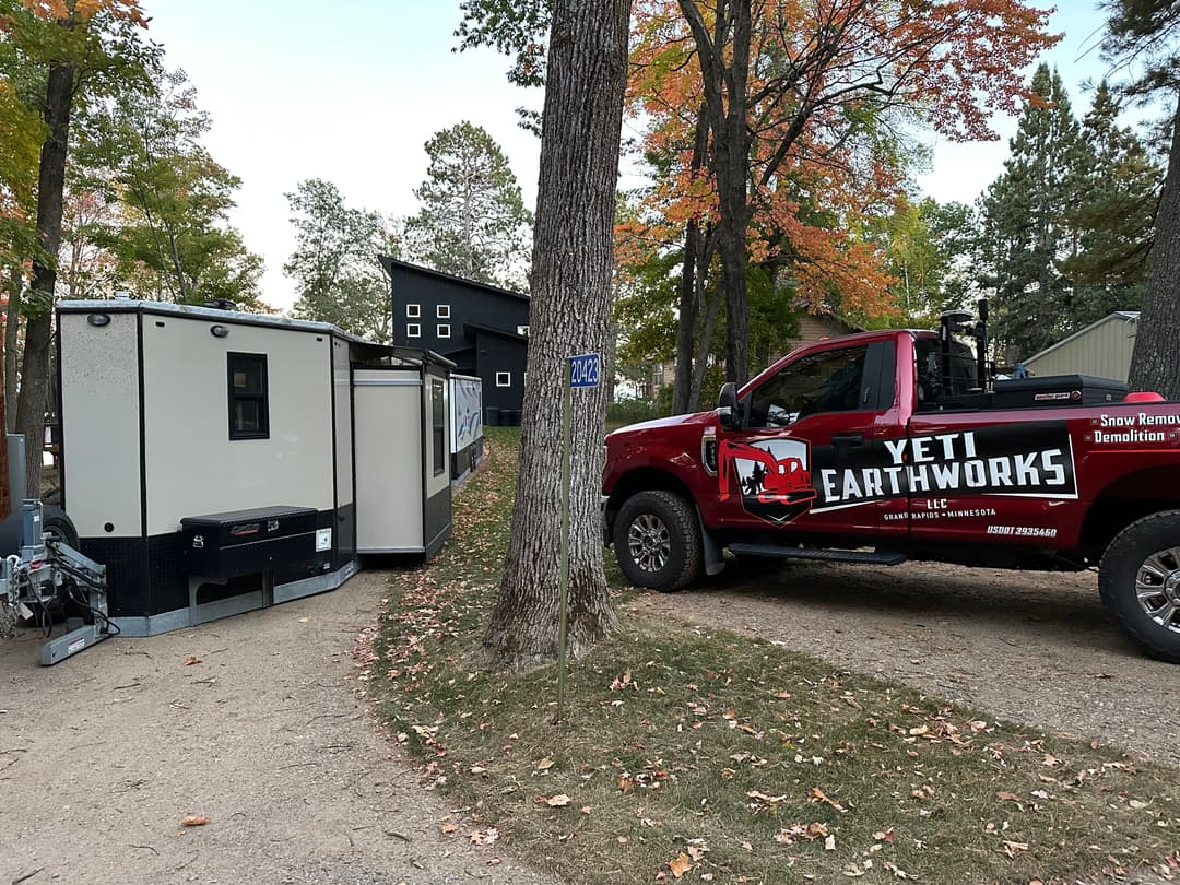Yeti Earthworks truck parked beside a demolition trailer in a wooded area.